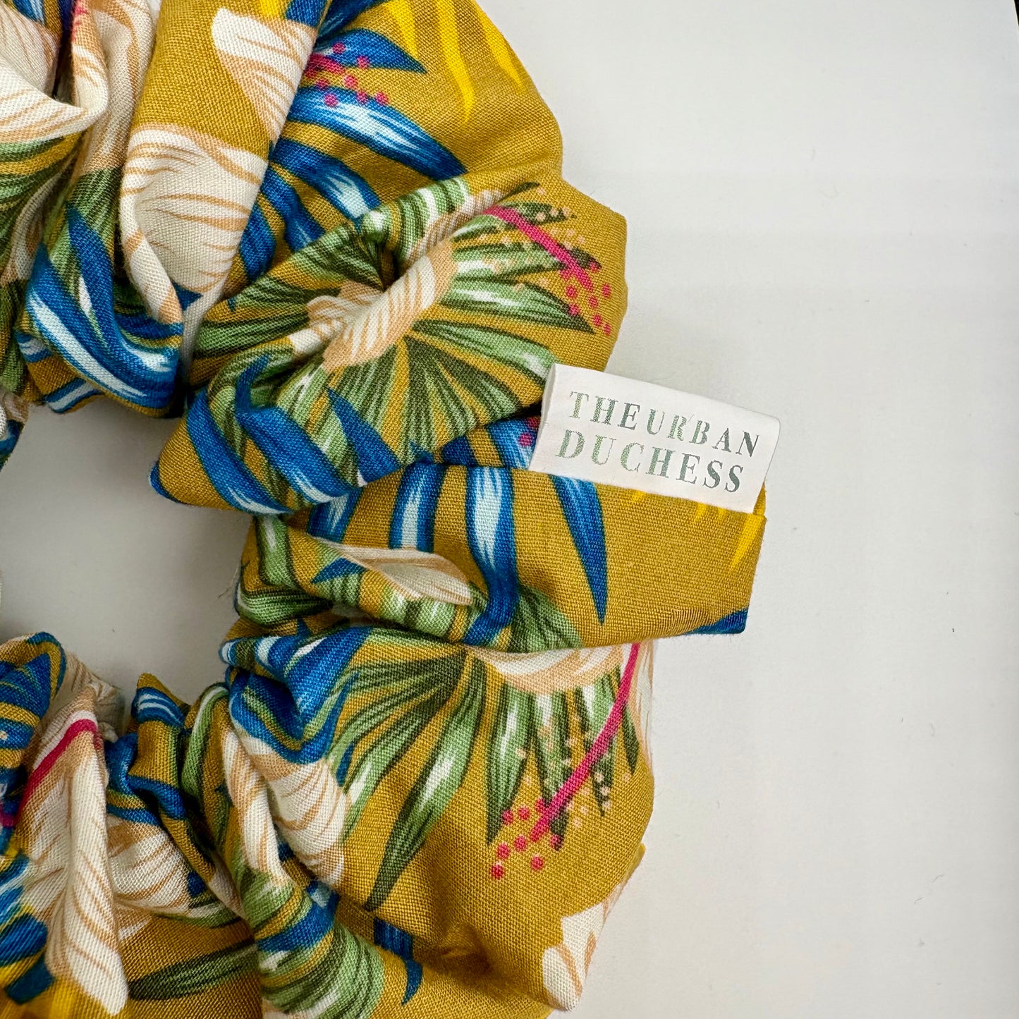 Close up of Hibiscus Sun scrunchie showing handmade brand label. Premium cotton, quality finish, made in Kent, UK, ready to ship and gift.